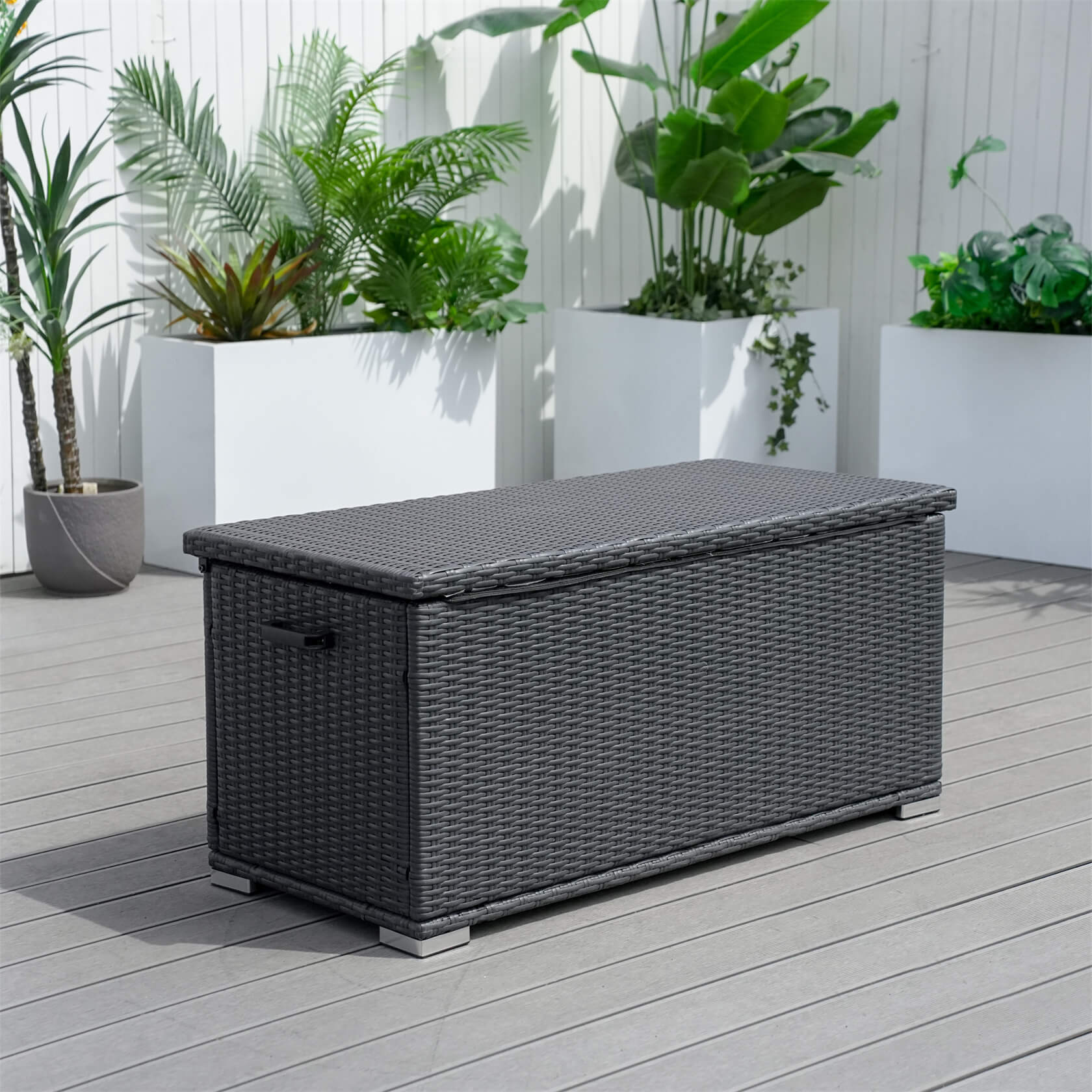 Black wicker storage box on a wooden deck with plants in the background